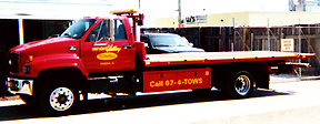 Red GMC flatbed, Call 674-TOWS on the bed