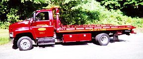 Red GMC flatbed parked in trees