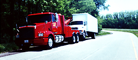 Red heavy wrecker towing on the road